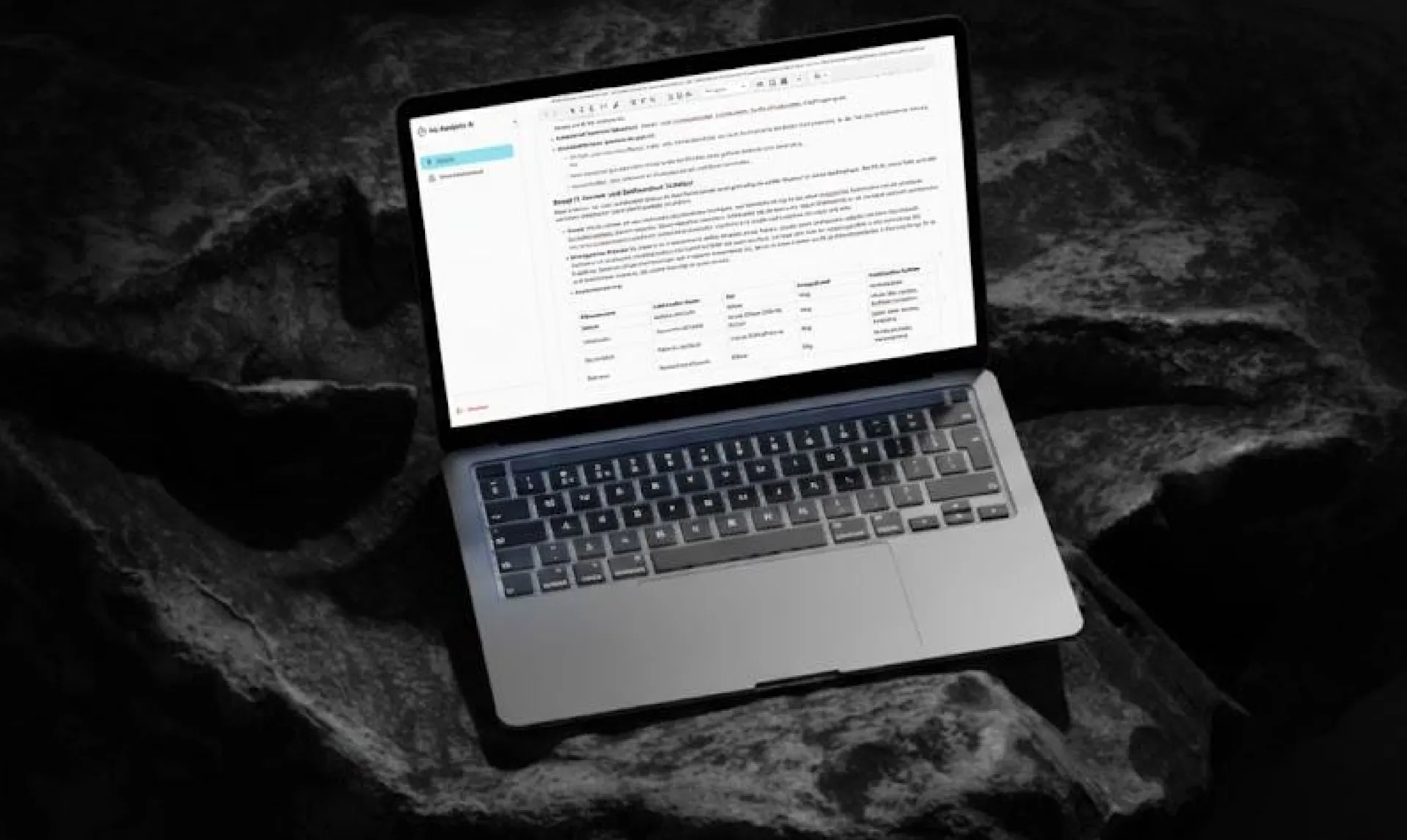 Laptop on dark rock showing a generated report with tables